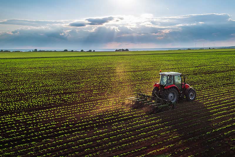 farm tractor tilling the soil under beautiful skies