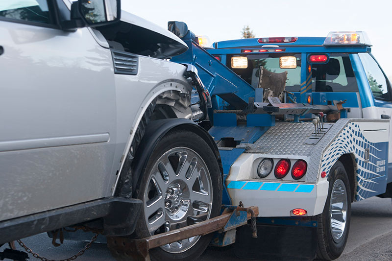 blue tow truck hauling a silver truck