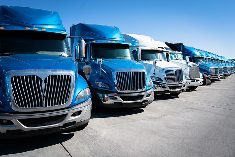 row of blue and white semi trucks on a sales lot