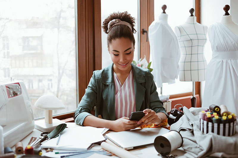 female dressmaker checking messages on her mobile phone