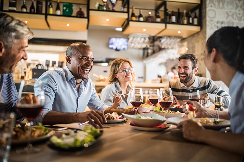 group of friends enjoying dinner and wine at a restaurant
