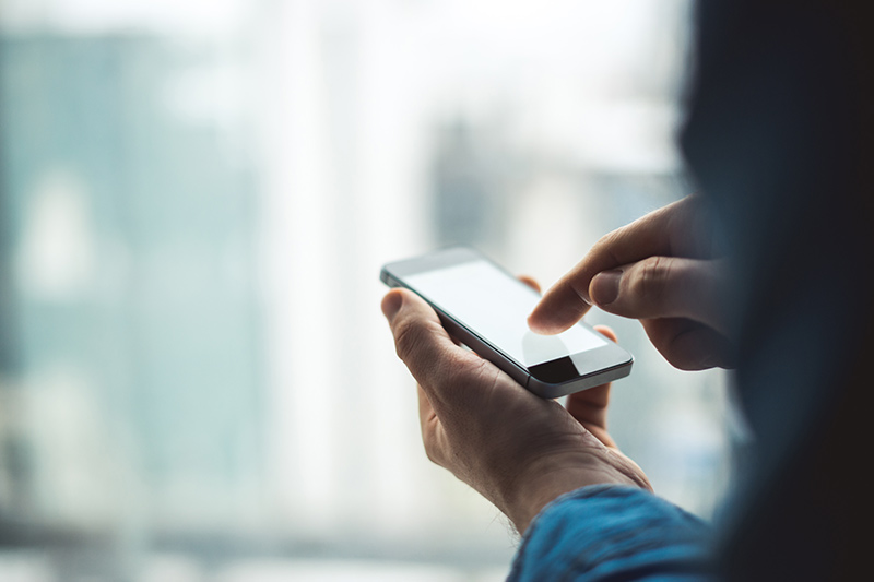 close up of a man's hands using a mobile phone