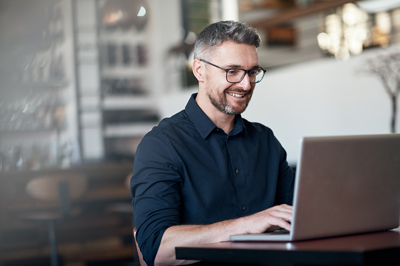 man with a beard using a laptop at a restaurant