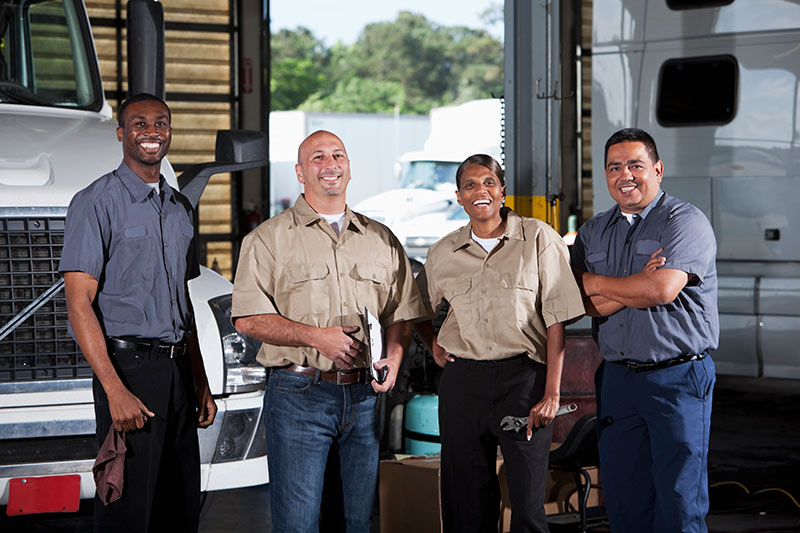 four happy truckers in a garage