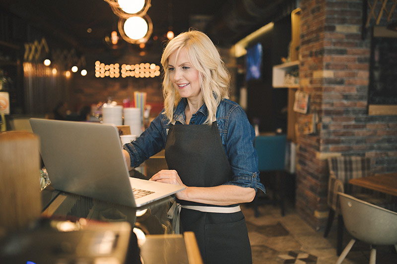 blonde female restaurant owner using a laptop computer